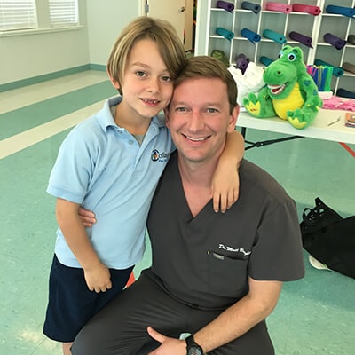 Doctor Bright hugging a little boy while they smile inside the dental office