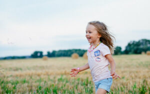 young girl on summer vacation running in field