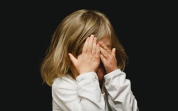 Little girl covering her face with her hands