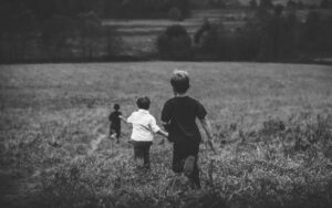 Black and white photo of 3 young boys running in a field against a background of trees at Smokey Mountains National Park
